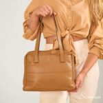 Bolsa de couro com divisórias modelo Cibeli na cor caramelo da Scarpan com detalhe de alça de ombro e logo dourado vista de costas.