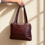 Bolsa de couro com divisórias Cibeli cor pinhão em couro legítimo com detalhes dourados. Foto costas da bolsa.