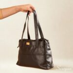 Bolsa de couro legítimo preta com três divisórias modelo Cibeli Scarpan vista de frente com alças de ombro.