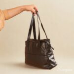 Bolsa de couro legítimo preta com três divisórias modelo Cibeli Scarpan vista de costas com alças de ombro.