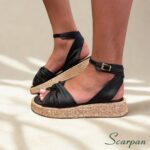 Detalhe lateral da sandália flatform feminina em couro preta com fechamento em fivela dourada.