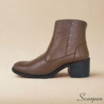 Detalhe lateral de bota de cano curto em couro whisky com pequenas tachas