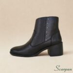 Detalhe lateral de bota de cano curto em couro com pequenas tachas metálicas