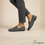 Movimento de calce com mocassim de couro cinza com enfeite dourado decorativo