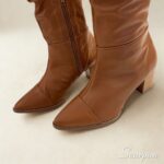 Detalhe frontal e zíper lateral funcional de bota de couro cano longo feminina