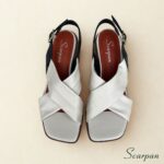 Sandália feminina em couro bicolor off-white e preto com fivela dourada visão de cima.