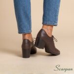 Visão do traseiro do Sapato oxford feminino em couro salto bloco na cor café com calça jeans.
