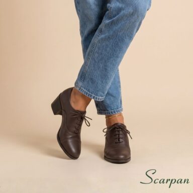 Sapato oxford feminino em couro salto bloco na cor café com calça jeans. Visão da frente.